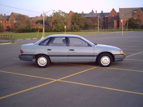 1986 Ford Taurus - Side view of a light blue 1986 Ford Taurus sedan in a parking lot.