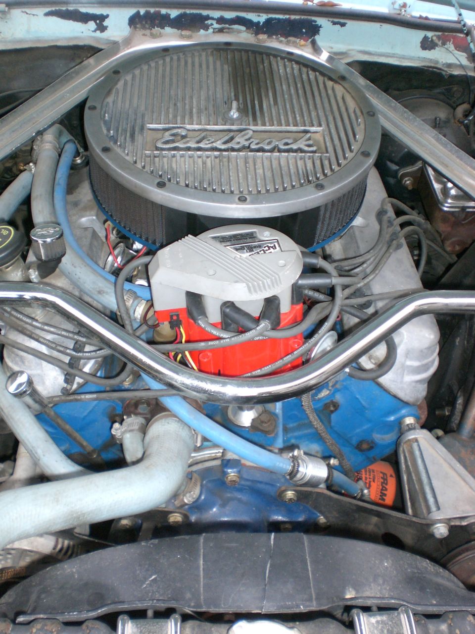 V8 engine bay with chrome Edelbrock air cleaner, red distributor, blue block and FRAM filter