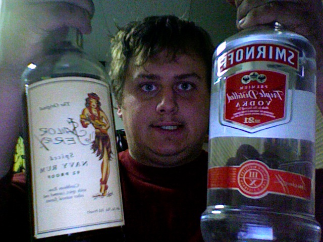 Person holding bottles of Sailor Jerry Rum and Smirnoff Vodka.