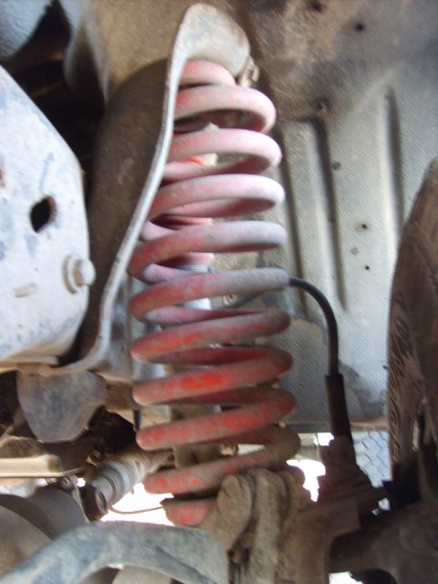 1989 Ford Bronco - This is a close-up view of the red coil spring suspension system on a 1989 Ford Bronco. The image shows the spring, shock absorber, and sur…