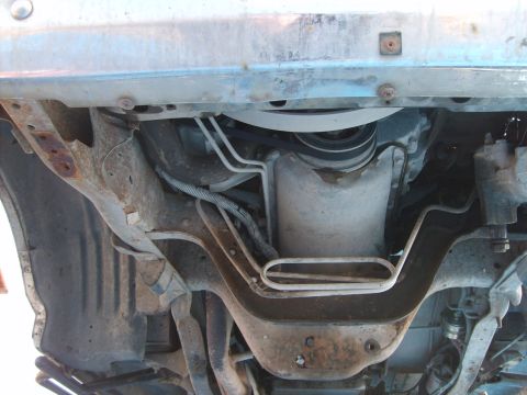 1989 Ford Bronco - Underside view of a vehicle's engine bay, showing the serpentine belt, pulleys, and various metal components. The area appears to be from a…