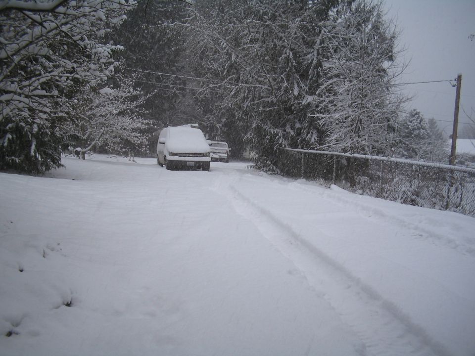 Snow-covered vehicle parked on a snowy road during a snowstorm