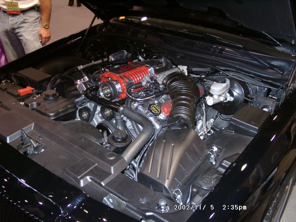 Supercharged V8 engine bay with red Roots blower on a black show car