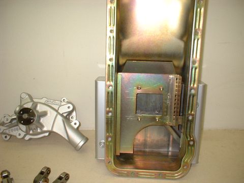 1970 Ford Mustang - Close-up of engine parts, including an oil pan and a water pump, laid out on a surface.