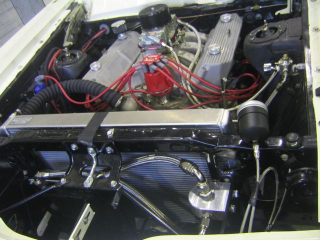 Engine bay with V8 engine, red spark plug wires, and aftermarket radiator