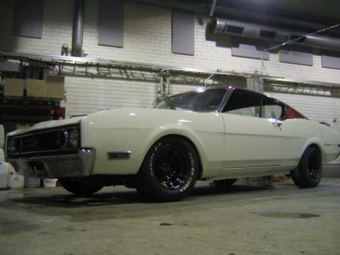1969 Mercury Cyclone - A white coupe with a red roof and black wheels is parked indoors, possibly in a garage or workshop.