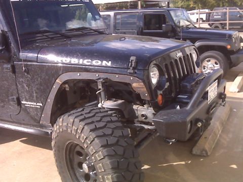 2008 Jeep Wrangler - A black Jeep Wrangler Rubicon is parked next to another Jeep, showing its front driver side and aftermarket bumper.
