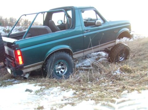 1996 Ford Bronco - This lifted 1996 Ford Bronco features a custom roll cage and appears to be navigating rough terrain.