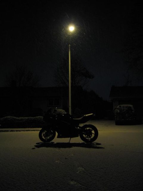 2008 Kawasaki Ninja R - A motorcycle sits on a snow-covered road illuminated by a single street lamp.