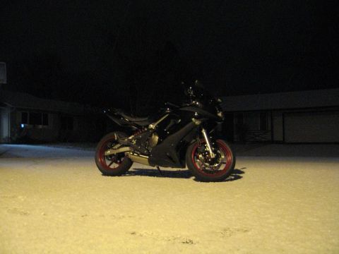 2008 Kawasaki Ninja R - A black motorcycle with red rims sits in a snowy area at night, with houses visible in the background.