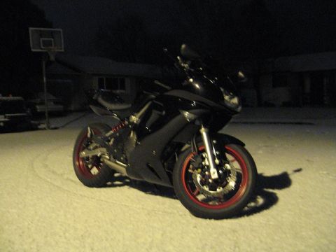 2008 Kawasaki Ninja R - Motorcycle with red rims sits in the snow under a dark sky.