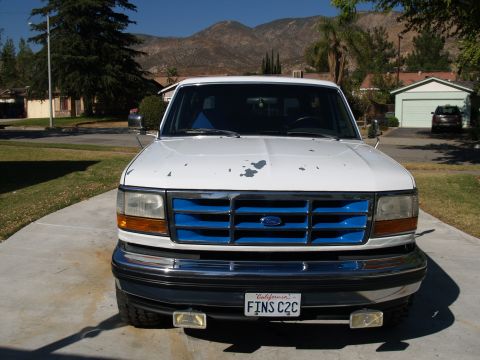 1993 Ford Bronco - Front view of a white Ford truck with a distinctive blue grille, parked in a driveway.