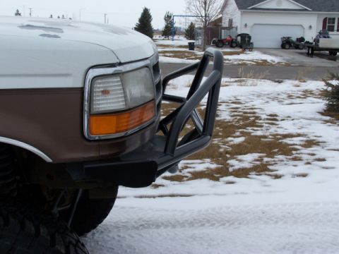 1995 Ford Bronco - Front view of a brown and white Ford truck with a black brush guard, parked in a snowy area.