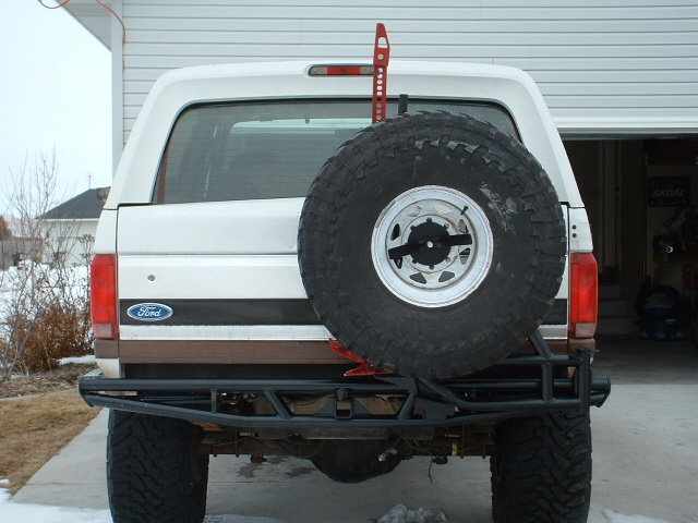 Rear view of a 1995 Ford Bronco with a spare tire mounted on a custom bumper and a Hi-Lift jack attached