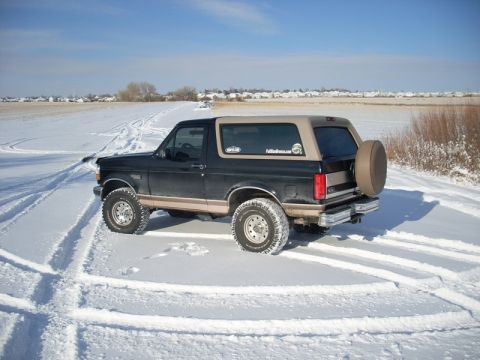 1996 Ford Bronco - A 1996 Ford Bronco is seen in a snowy field with tire tracks around it.