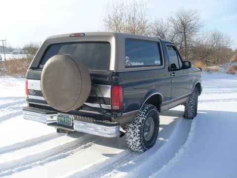 1996 Ford Bronco - A Ford Bronco navigates through a snowy landscape, its tires kicking up snow.