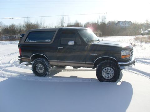 1996 Ford Bronco - A 1996 Ford Bronco with off-road tires sits in a snowy landscape, its two-tone paint job visible.