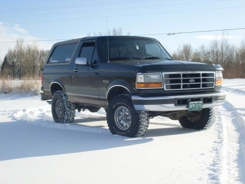 1996 Ford Bronco - Ford Bronco with large tires sits in a snowy landscape under a clear sky.