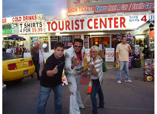 People posing outside Tourist Center shop, yellow Mustang partly visible at left