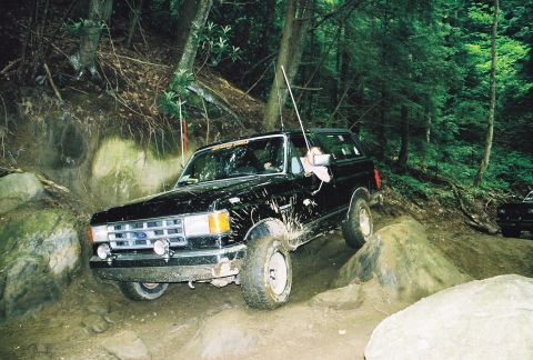 1991 Ford Bronco - This 1991 Ford Bronco tackles a challenging off-road course with another vehicle visible in the background.