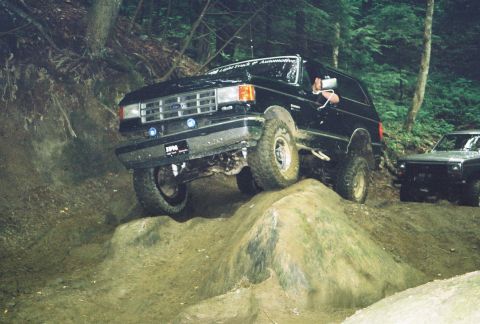1991 Ford Bronco - 1991 Ford Bronco navigating a challenging off-road obstacle course with another vehicle in the background.