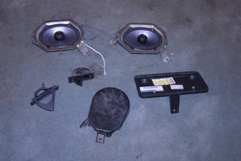1993 Ford Bronco - Assorted car interior parts including speakers and trim pieces are displayed on a carpeted floor.