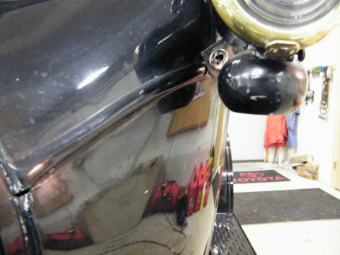 1915 Ford Model T - Close-up view of a black car's fender and headlight assembly, showing reflections on the glossy surface.