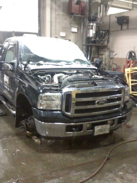 1992 Ford Bronco - A black Ford truck is parked inside a garage with its hood open and snow covering the windshield.