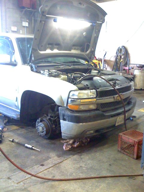 1992 Ford Bronco - Pickup truck undergoing maintenance in a workshop, with the hood and front wheel removed.