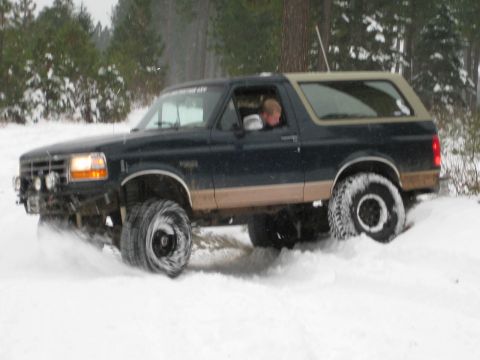1995 Ford Bronco - A dark blue and tan Ford Bronco navigates through a snowy landscape.