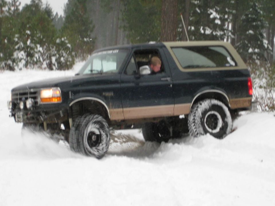 Dark blue and tan Ford Bronco driving through snow