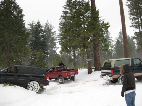 1995 Ford Bronco - A Ford Bronco is being towed in a snowy forest scene with other vehicles present.