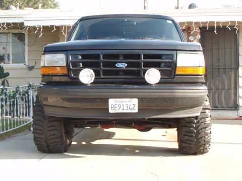 1995 Ford Bronco - Front view of a black 1995 Ford Bronco, aftermarket driving lights and a lifted suspension.