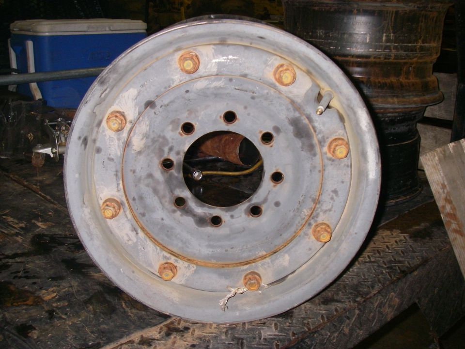 Gray steel wheel rim with 6 lug nuts, showing rust and wear