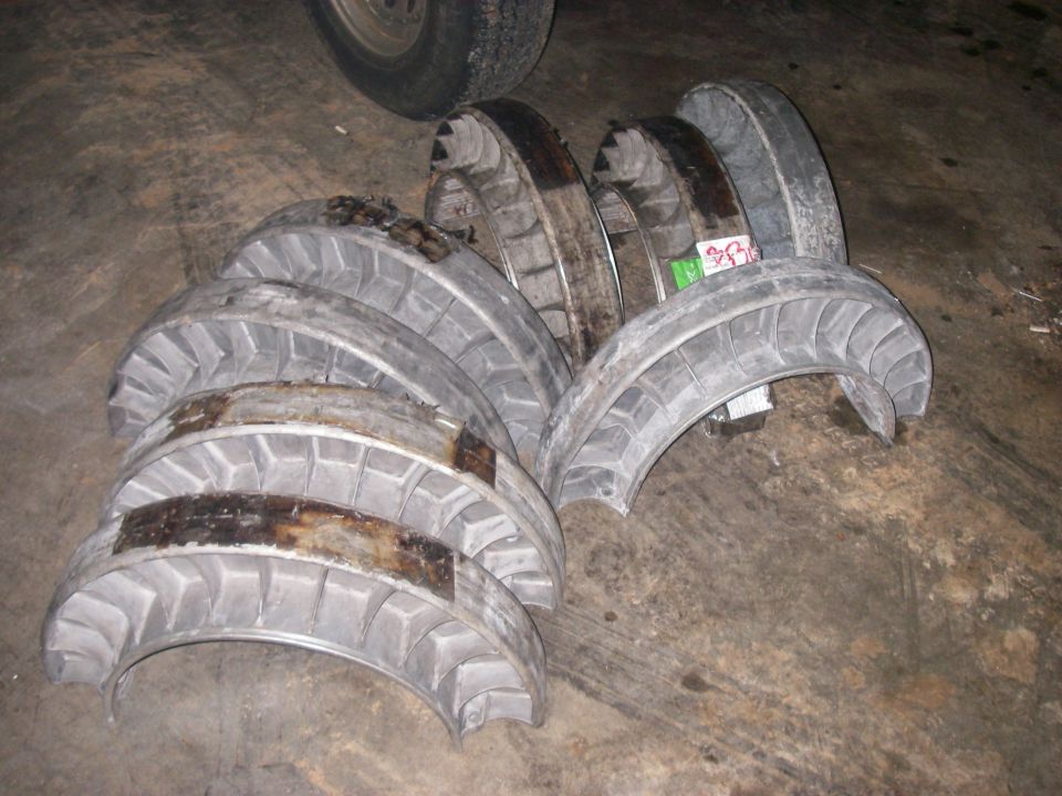 Pile of engine bearings on a concrete floor. A tire is visible in the upper left