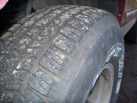 1977 Ford F-150 - A close-up view of a tire shows white lettering on its sidewall, with dirt and debris on the tread.