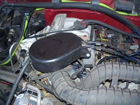 1977 Ford F-150 - Close-up view of engine components, including the air intake system and a black protective cover.