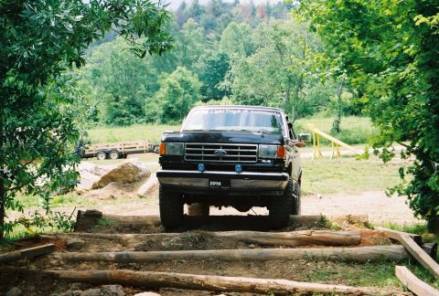 1991 Ford Bronco - 1991 Ford Bronco navigating an off-road course with log obstacles.