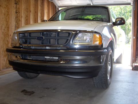 2007 Ford Mustang - This white Ford F-150 pickup truck is parked in a garage, showing its front grille and bumper.