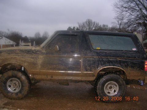 1994 Ford Bronco - Muddy 1994 Ford Bronco parked outdoors on a cloudy day.