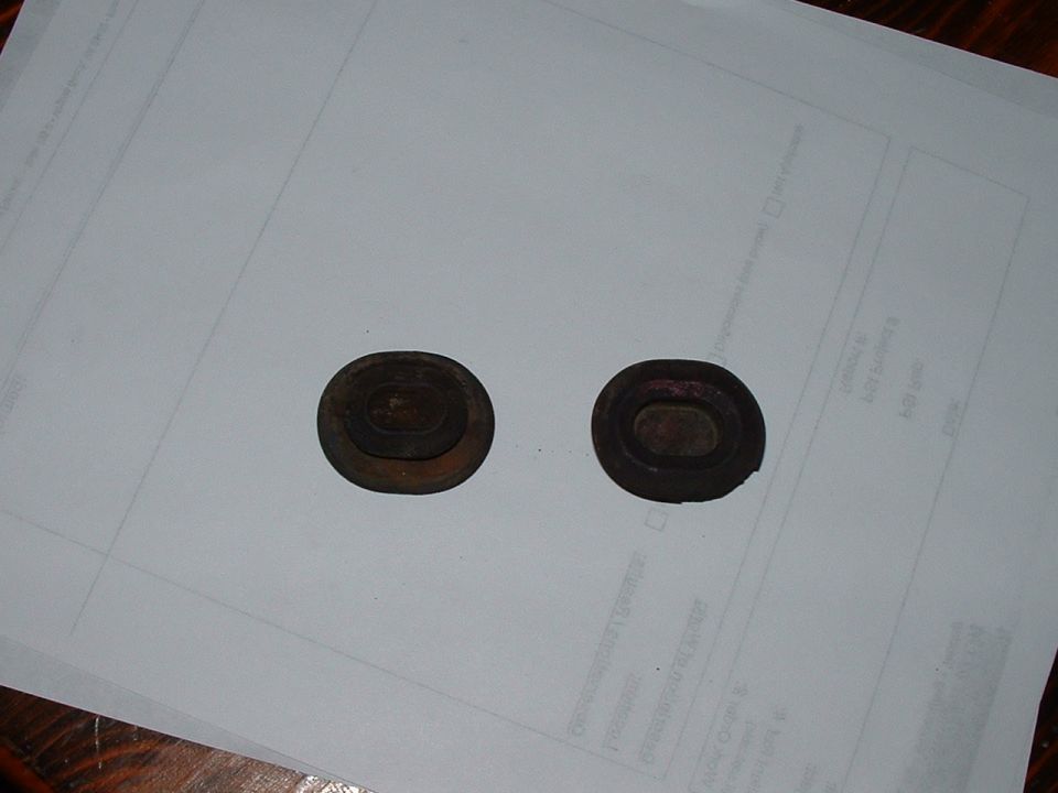 Two dark, oval rubber grommets on a white paper
