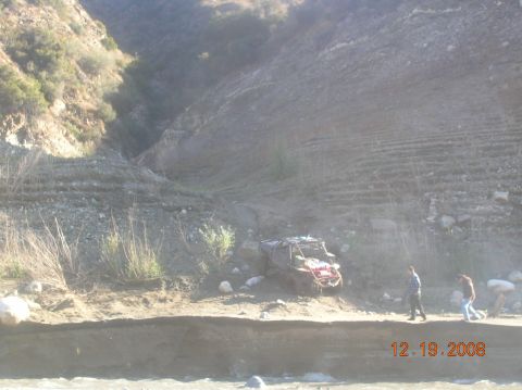 1985 Ford Bronco - Off-road vehicle partially submerged in a dry riverbed with onlookers.