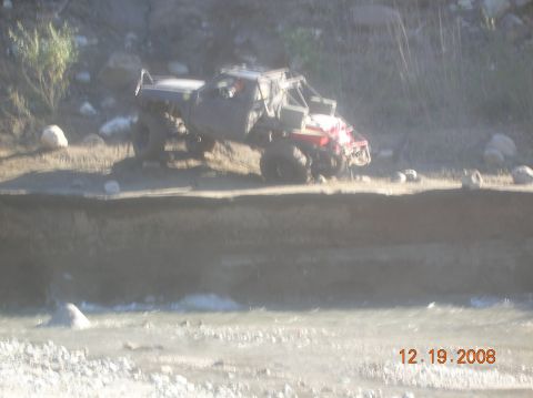 1985 Ford Bronco - A heavily modified off-road vehicle navigates a dirt path next to a body of water.