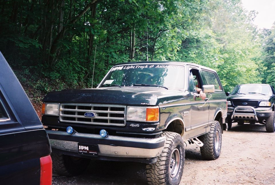 Black Ford Bronco with lifted suspension and off-road tires, parked on a dirt road