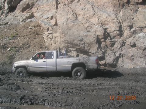 1985 Ford Bronco - A silver pickup truck is stuck in thick mud near a rocky cliff face, with a date stamp of 12.20.2008 visible.