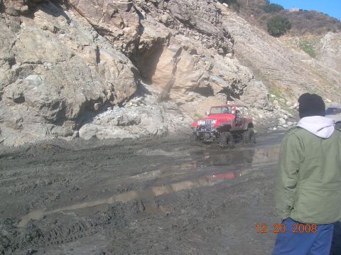 1985 Ford Bronco - Off-roading adventure in a red Jeep Wrangler on a muddy trail.
