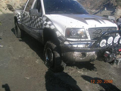 1985 Ford Bronco - This truck is covered in mud and appears to be stuck on a dirt road.