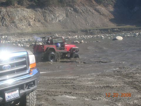 1985 Ford Bronco - A red Jeep is seen off-roading in a muddy, watery area, with the front of a Ford truck visible in the foreground. The date 12-20-2008 is vi…