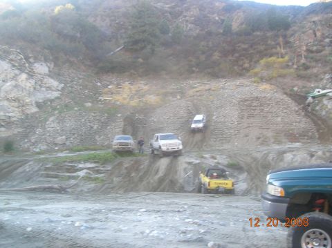 1985 Ford Bronco - Several off-road vehicles are navigating a steep, muddy embankment on a sunny day. A yellow Toyota pickup truck is visible in the foregroun…