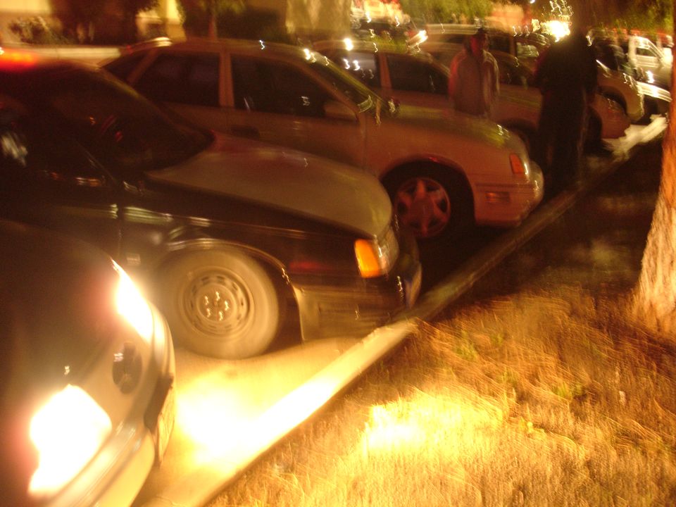Row of Ford Taurus sedans parked along a curb at a night car meet